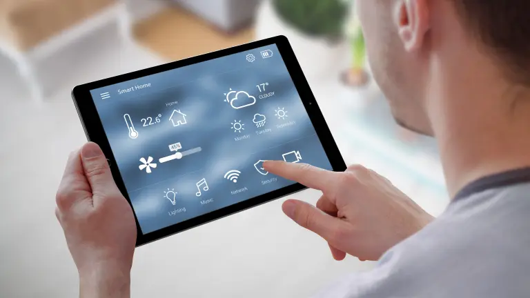 Ein Mann der ein Tablet hält mit der Steuerung von Smart Home Systemen
