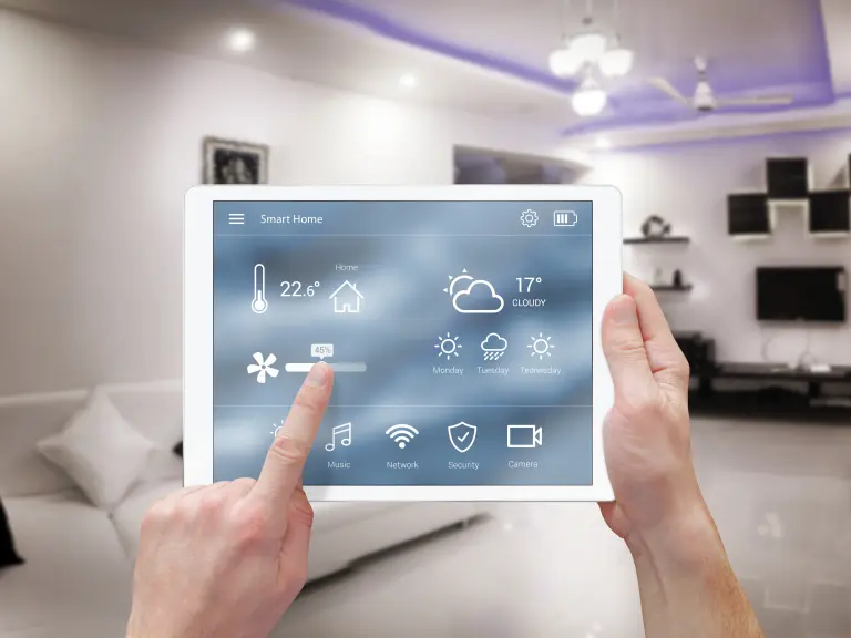 Zwei Hände halten ein Tablet, das Smart Home-Funktionen steuert